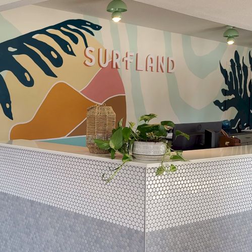 Reception area in a SurfLand-themed office with a colorful wall mural and desk under green ceiling lights.